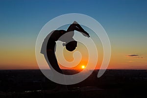 Woman practicing yoga at sunset - drop back, wheel pose