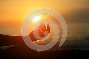 Woman practicing yoga at sunset or morning sea beach