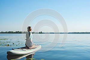 Woman is practicing yoga on a SUP board