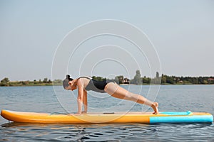 Woman practicing yoga on SUP board on river