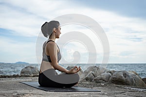 woman practicing yoga during surrealistic sunset at the seaside.