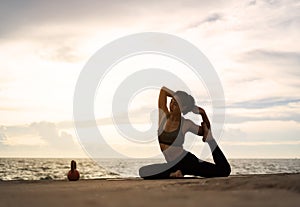 woman practicing yoga during surrealistic sunset at the seaside.