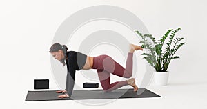 A woman practicing yoga, training in sportswear on a mat, performing the Ardha Hanumanasana exercise