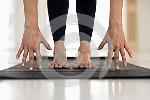 Woman practicing yoga, uttanasana pose, hands and feet close up