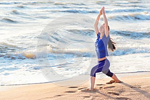 Woman practicing yoga warrior position on the beach