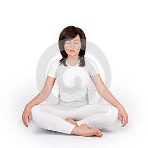 Woman practicing yoga on white background. Girl wearing white meditating with closed eyes, sitting in lotus position or