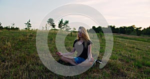 Woman practises yoga at sunrise under the tree. Young spiritual girl meditates in lotus pose nature outdoors, slow motion