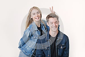 Woman pranking her boyfriend with bunny ears. Studio shot over white background