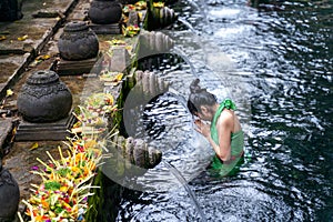 Woman pray and bath holy spring waters in Tirta Empul water temple, Bali, Indonesia.