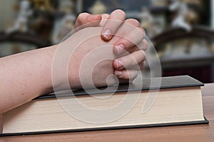 Woman is praying in church. Clasped hands on bible