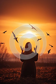 Woman praying and free the birds to nature on sunset background AI generated