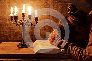 Woman praying, hands clasped together on her Bible