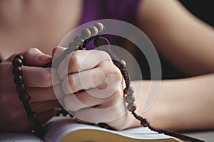 Woman praying with her bible and rosary beads
