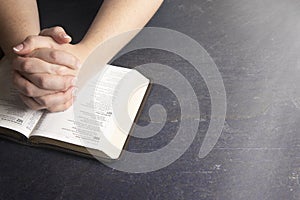 Woman Praying with Her Hands Clasped on a Bible