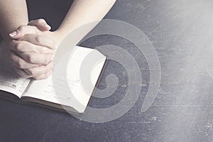 Woman Praying with Her Hands Clasped on a Bible