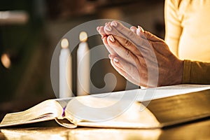 Woman praying with her hands over the bible, hard light