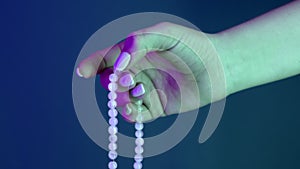 Woman praying and holding mala beads in hand for counts during mantra meditations. Lady on blue background. Spirituality