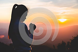 Woman praying in the morning on the sunrise background. Christianity concept. Pray background. Faith hope love concept