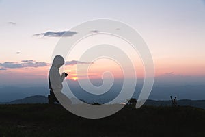 A women is praying to God on the mountain. Praying hands with faith in religion and belief in God on blessing background. Power of