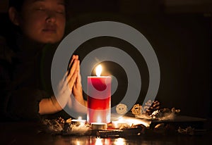 Woman Praying and worship to GOD Using hands to pray in religious beliefs and worship christian with Red Candle with fire against