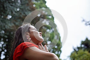 A woman prays while being drenched in rain