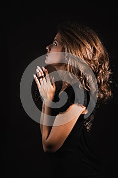 Woman prays on a black background