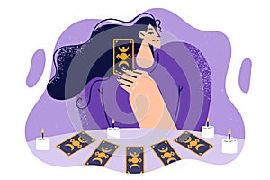 Woman predictor or fortune teller with tarot cards laid out on table with candles predicts future.