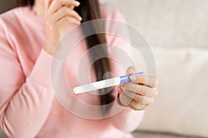 Woman with pregnancy test positive result, focus on foreground 2 stripes