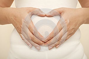 Woman pregnant do hand heart at paunch photo