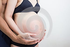 Woman are pregnant with hands of her husband on white background. The abdominal section of the womb.