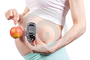 Woman in pregnant holding glucose meter and apple, diabetes and healthy nutrition during pregnancy