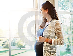 Woman, pregnant and thinking on future at window, hope and maternity, love and hands on stomach. Mother, healthy and