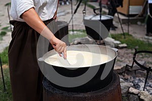 Woman prepare cornmeal, maize or quinoa porridge in cast iron cauldron