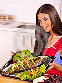 Woman prepare fish in oven.