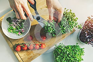 Woman prepare fresh raw vegetarian salad from microgreens and vegetables