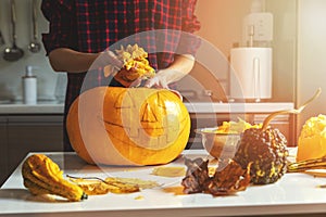 Woman prepare pumpkin for halloween holiday decoration remove seeds at home kitchen