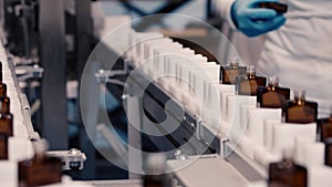 A woman prepares empty perfume bottles on a mechanical line