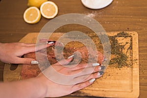 A woman prepares fish, cutting fish on a wooden board, the cook season the trout.