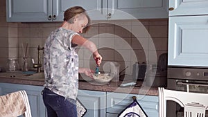 Woman prepares a food and looks on smartphone