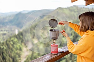 Woman prepares food while traveling in mountains
