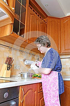 A woman prepares food using a mixer