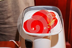 A woman prepares fresh healthy juice from tomatoes. Juicer at work. Diet concept for a healthy lifestyle