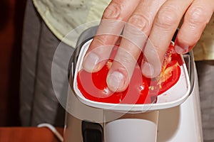 A woman prepares fresh healthy juice from tomatoes. Juicer at work. Diet concept for a healthy lifestyle