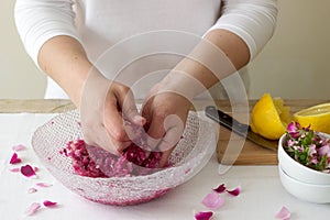 A woman prepares jam from roses, ingredients for jam from roses. Rustic style.