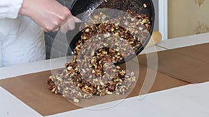 A woman prepares kozinak from nuts. Lay the toasted nuts on a non-stick mat. Sunflower seeds, peanuts and walnuts roasted in sugar