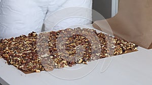 A woman prepares kozinak from nuts. Places the toasted nuts on a non-stick mat. Sunflower seeds, peanuts and walnuts roasted in