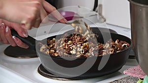 A woman prepares kozinak from nuts. Roasts sunflower seeds, peanuts and walnuts in sugar and honey. Medium plan