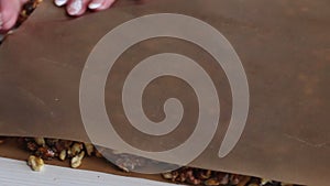 A woman prepares kozinak from nuts. Rolls out toasted nuts on a non-stick mat. Sunflower seeds, peanuts and walnuts roasted in