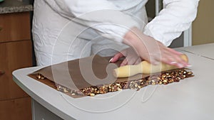 A woman prepares kozinak from nuts. Rolls out toasted nuts on a non-stick mat. Sunflower seeds, peanuts and walnuts roasted in