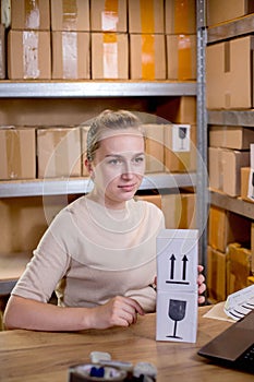 Woman prepares a product box for delivery to a customer. The box with the sticker is fragile. Online business, e